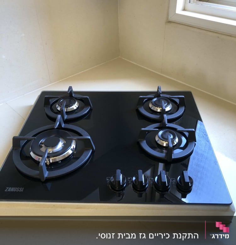 כיריים גז שחורות עם ארבעה מבערים וכפתורי שליטה